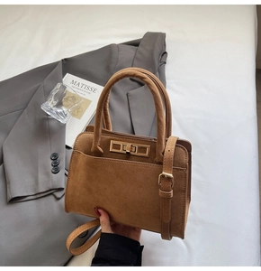 Detail of tan suede tote bag with gold metal twist lock and adjustable shoulder strap