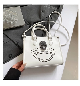 Détail d'un sac cabas blanc avec motif de crâne argenté et clous décoratifs posé