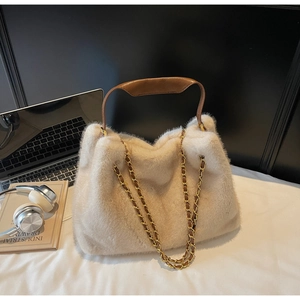Detail of plush faux fur handbag with brown leather handle and gold chain strap accents