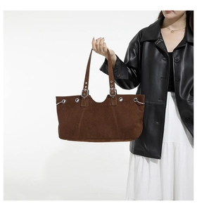 Detail view of brown matte tote bag featuring silver eyelets and buckle accents