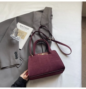 Detail view of burgundy suede tote with gold hardware clasp and adjustable strap