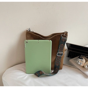 Brown bucket bag detail showing a colorful floral wide strap with a tablet inside for scale