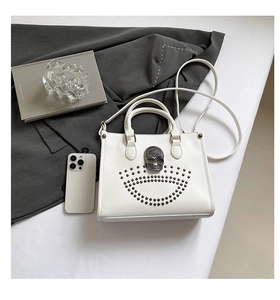Détails du sac blanc orné d'une boucle tête de mort en strass et rivets métalliques