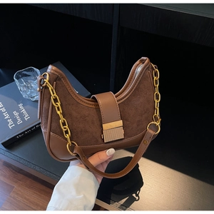 Detail of retro crescent shoulder bag featuring contrasting textures and a golden chain strap