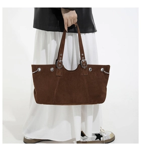Detail view of dark brown faux suede tote bag with silver eyelets and adjustable strap