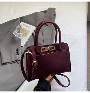 Detailed shot of dark wine red suede handbag featuring a gold rectangle twist lock