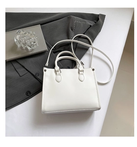 Détail d'un sac cabas blanc minimaliste en similicuir avec boucles métalliques argentées