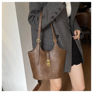 Close-up of brown synthetic leather tote bag featuring gold metal buckle and lychee grain texture