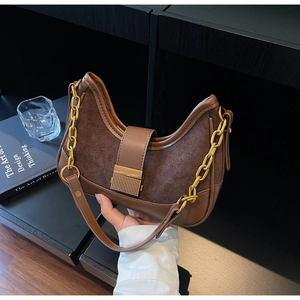 Detail of dark brown crescent bag featuring leather splicing and gold metal buckle