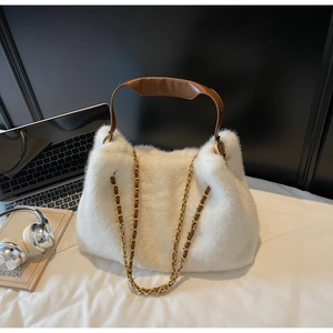 Detail of white plush shoulder bag featuring brown leather handle and gold chain strap