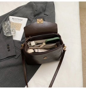 Detail view of brown retro crossbody bag interior compartments and daily essentials