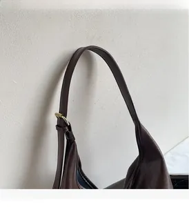Close-up of dark brown leather tote bag showing golden adjustable buckle details
