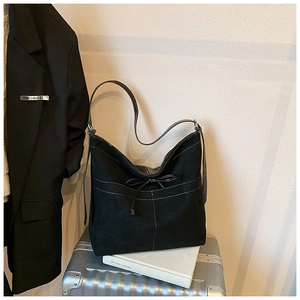 Détail du sac fourre-tout en daim noir avec surpiqûres blanches et nœud décoratif
