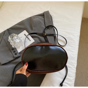 Vue détaillée du fond en cuir noir et du tissu en daim marron sur un sac seau bandoulière