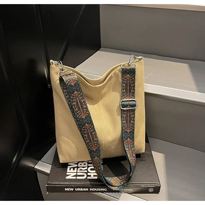 Detail of beige canvas bucket bag with colorful geometric woven bohemian shoulder strap
