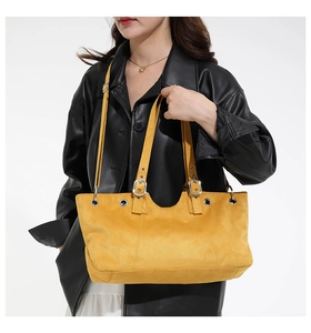 Detail of a bright yellow suede tote bag with silver hardware and adjustable strap