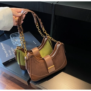 Detail view of suede patchwork underarm bags with gold chain straps in tan and green
