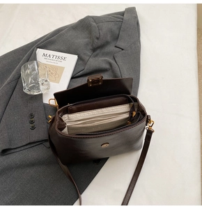 Detailed view of dark brown leather handbag featuring internal compartments and hardware