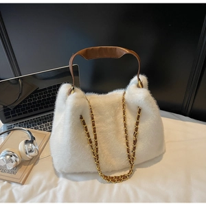 Detail of white faux fur tote bag with brown leather handles and gold metal chain strap