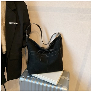 Détail du sac cabas noir montrant des surpiqûres blanches et un décor de nœud élégant