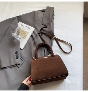 Detail of dark brown suede tote bag with golden hardware and adjustable strap