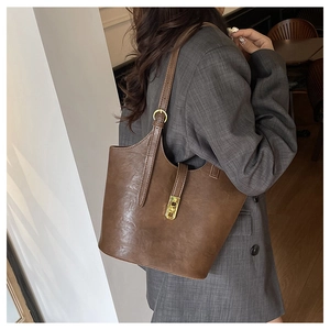 Close-up of brown leather tote bag with gold metal buckle and adjustable shoulder strap