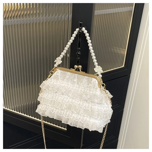 Détail d'un sac à main en dentelle blanche avec anse en perles et fermoir papillon doré