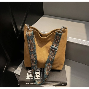 Close-up of wide jacquard shoulder strap with geometric pattern on brown canvas bucket bag