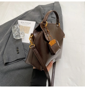 Detail of dark brown leather handbag with gold hardware and matching mini charm pouch