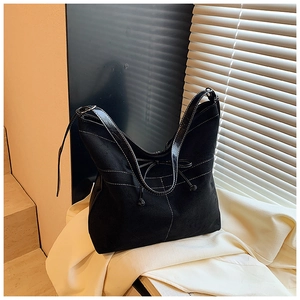 Détail du sac cabas noir en daim avec surpiqûres blanches et nœud décoratif élégant