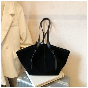 Detail of black faux suede tote bag featuring a decorative knotted leather shoulder strap