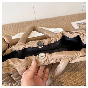 Détail du fermoir magnétique en métal sur un grand sac cabas matelassé beige