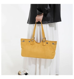 Detail of yellow tote bag with silver metal eyelets and adjustable shoulder strap detail