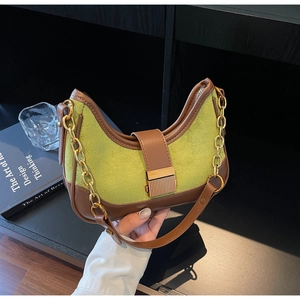 Detail showing contrast green suede and brown leather texture with golden metal chain