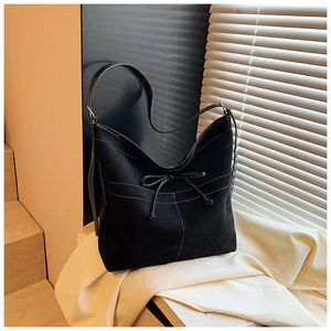 Détail du sac cabas en daim avec surpiqûres blanches contrastées et nœud sur la bandoulière