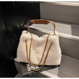 Detail of white plush faux fur handbag with brown leather handle and gold chain strap