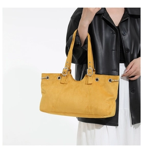 Detail of matte mustard yellow tote bag with silver metal eyelets and adjustable buckle