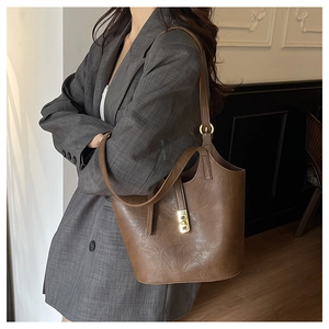 Detail of vintage brown leather bucket bag with gold metal hardware and adjustable strap