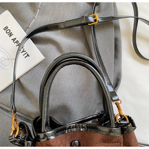 Détail du sac seau en daim marron et cuir verni noir avec des garnitures dorées