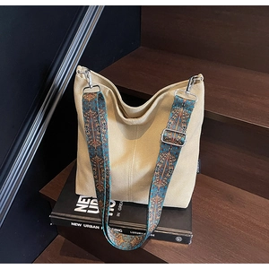 Detail of beige canvas tote bag featuring adjustable ethnic geometric patterned strap