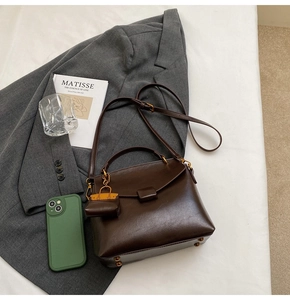 Detail of vintage dark brown leather handbag with mini charm and adjustable strap