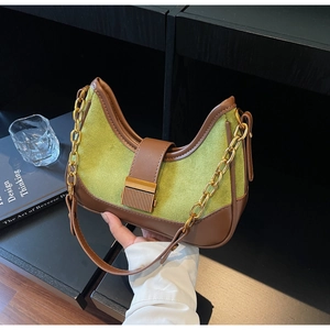 Detail of green suede crescent bag with brown leather trim and golden chain strap