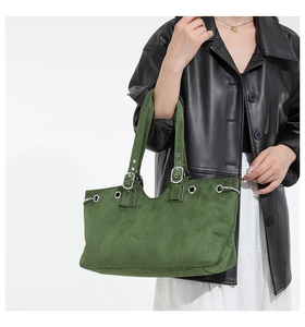Detail of dark green suede tote bag featuring silver eyelets and adjustable buckle strap