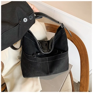 Détail du sac cabas en daim noir avec surpiqûres blanches et bandoulière réglable