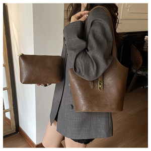 Close-up of brown vintage leather tote bag set with metal buckle and matching clutch