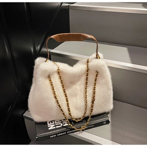 Detail of white fluffy faux fur handbag with brown leather handle and gold chain straps