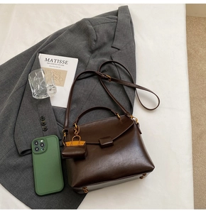 Deep brown square handbag with matching mini bag charm on stylish grey blazer setting