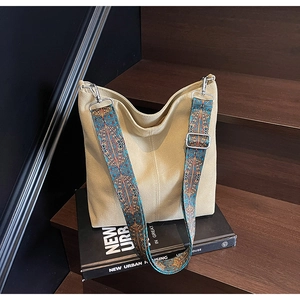Detail of canvas tote bag with bohemian colorful wide strap on a wooden staircase
