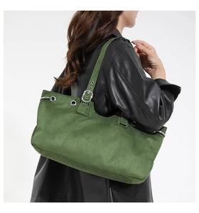 Detail of green suede tote bag showing metallic eyelets and adjustable strap on a model