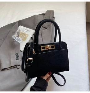 Detail of black suede tote bag featuring a golden metal buckle and textured material
